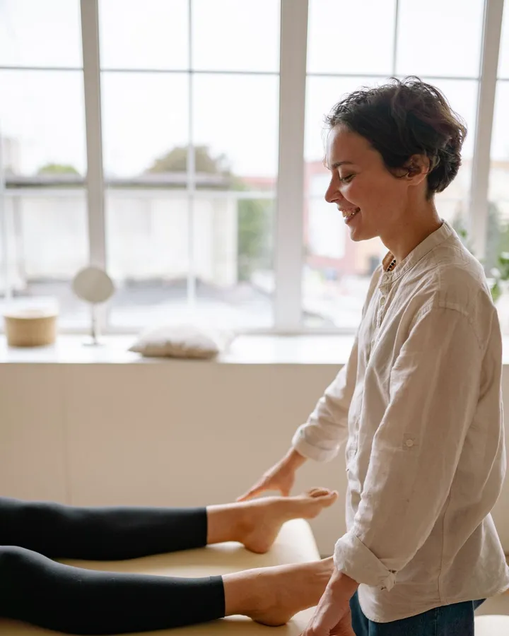 Priya Marlow smiling while she works with a patient on a treatment table.